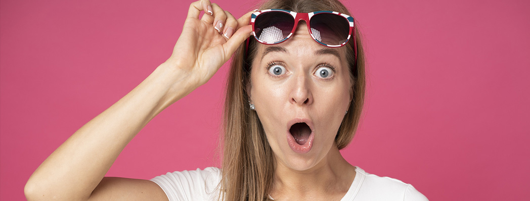 Woman surprised taking off rose coloured glasses